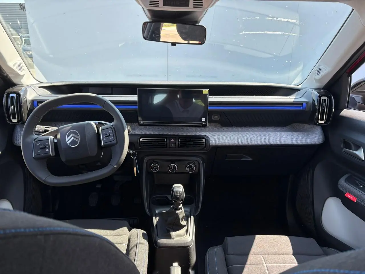 Vue intérieure avant de la Citroën C3 2025 avec tableau de bord gris, écran tactile et volant multifonction noir.