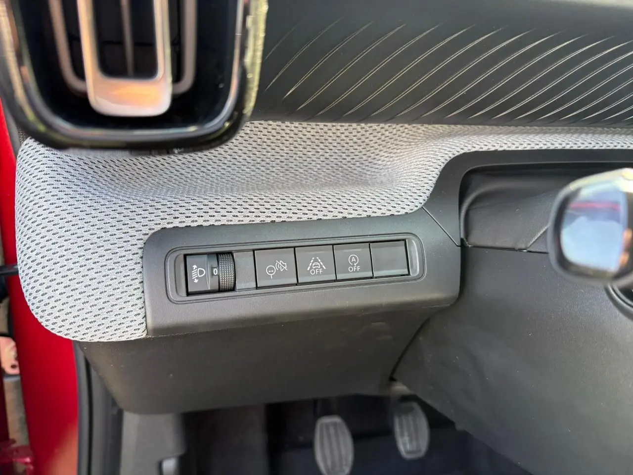 Vue rapprochée des commandes d'assistance au conducteur sur la planche de bord grise d'une Citroën C3 rouge Elixir toit noir.