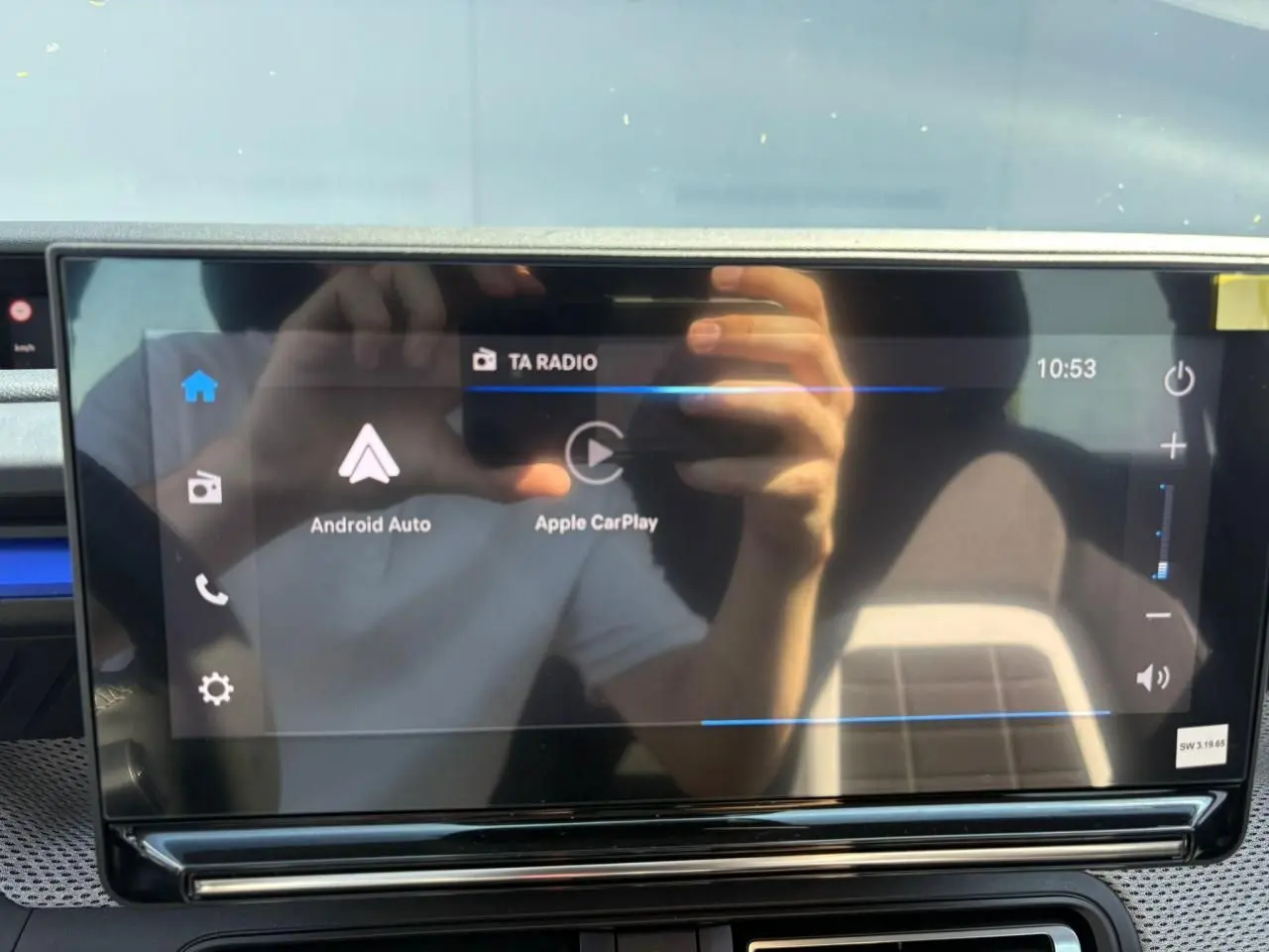 Écran tactile central de la Citroën C3 2025 affichant Android Auto et Apple CarPlay, reflet d'une personne visible.