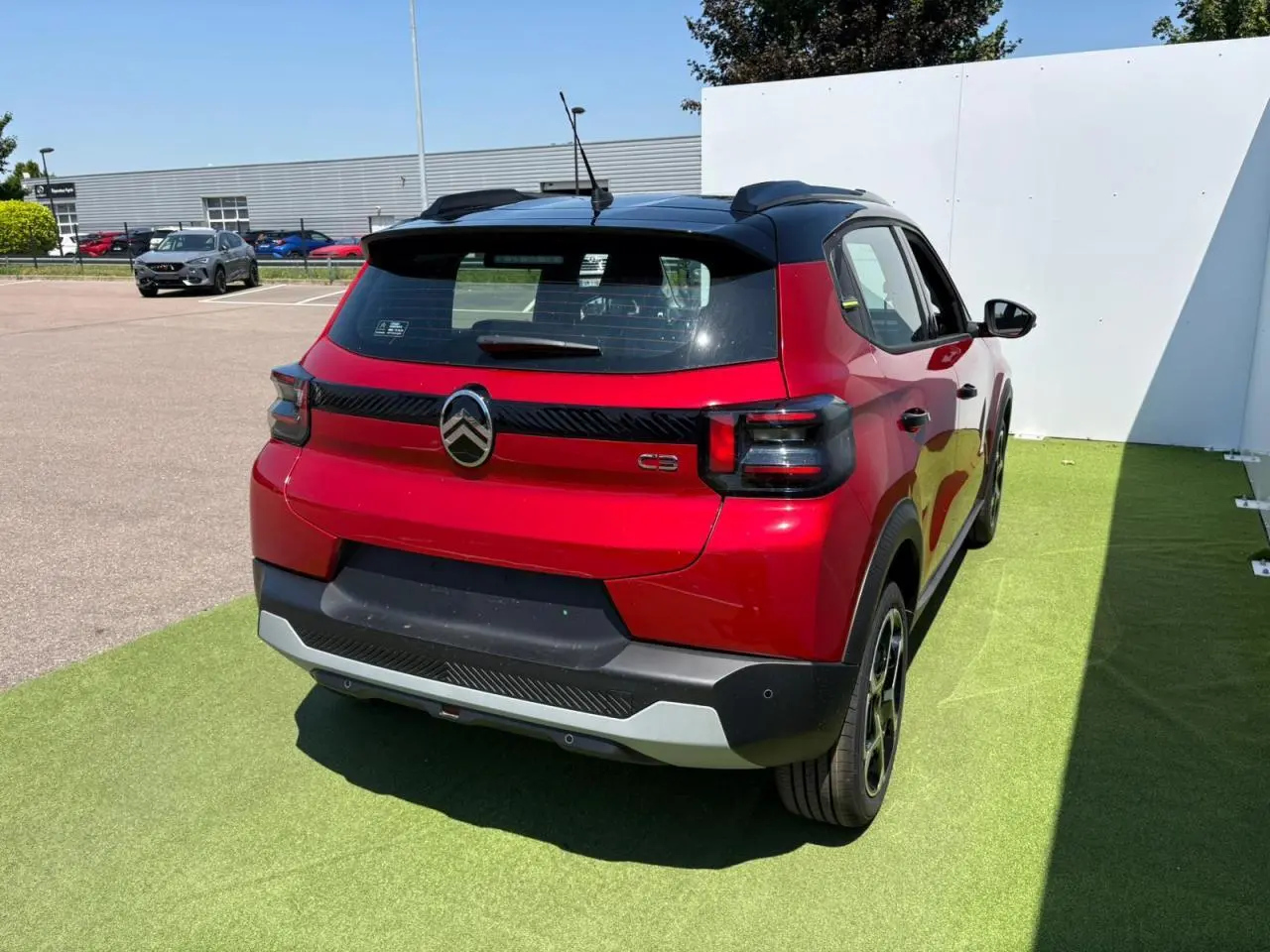 Vue 3/4 arrière droite d'une Citroën C3 2025 rouge Elixir avec toit noir et feux arrière fumés.