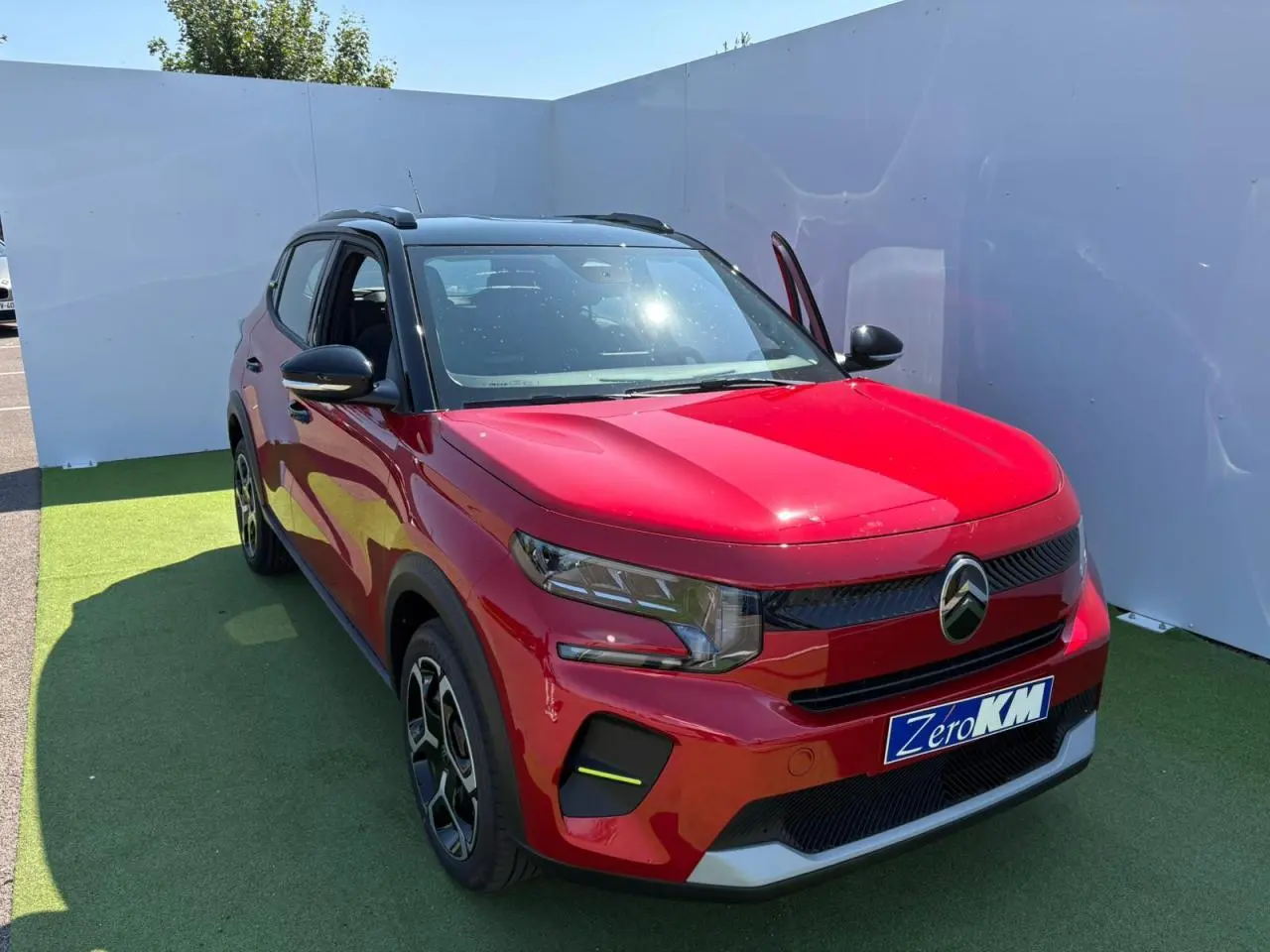 Citroën C3 2025 rouge Elixir avec toit noir, vue 3/4 avant droit, porte avant ouverte, jantes noires et grises.