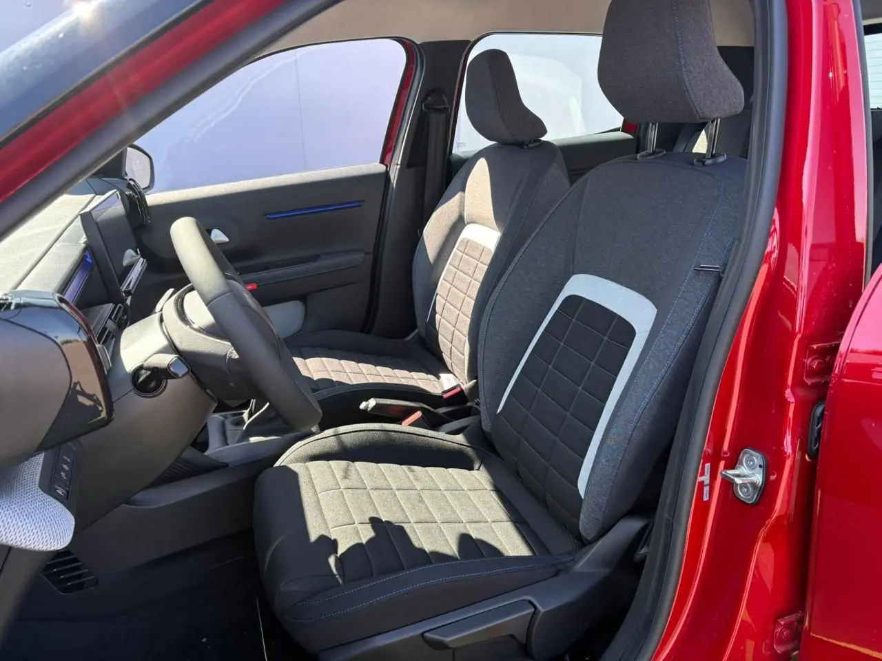 Vue intérieure côté gauche des sièges avant gris à motifs carrés d'une Citroën C3 rouge Elixir toit noir 2025