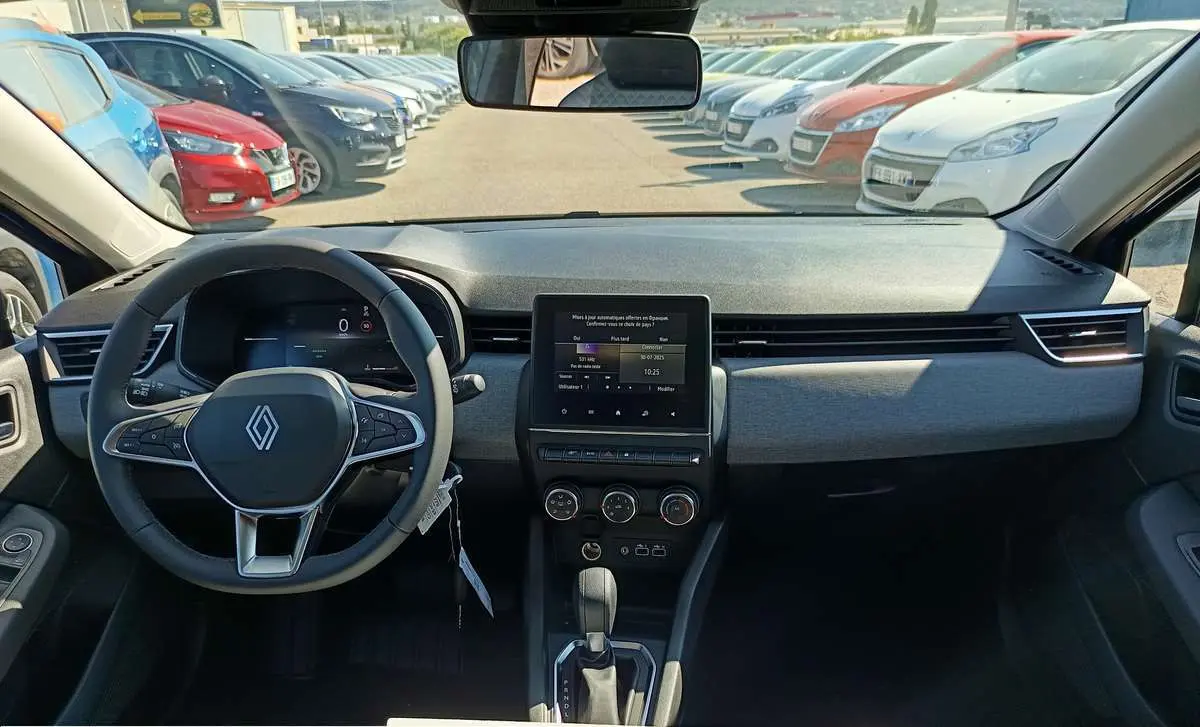 Vue intérieure avant du tableau de bord et volant de la Renault Clio 2025 gris schiste avec écran tactile central et boîte auto.