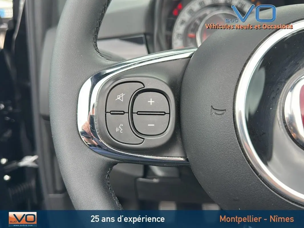 Gros plan sur les commandes gauche du volant de la Fiat 500C noire 2024, mettant en valeur les boutons de volume et de mute.