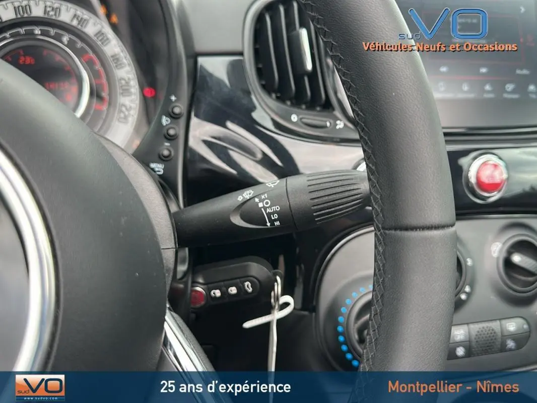 Vue rapprochée du volant et du tableau de bord noir de la FIAT 500C 2024 avec commandes et aérateurs visibles.