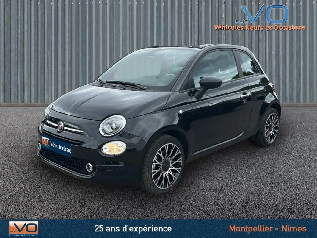 Vue 3/4 avant d'une FIAT 500C noire 2024 avec jantes alliage et toit rigide fermé sur fond urbain.