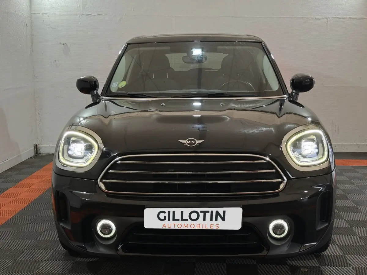 Vue frontale d'un MINI Countryman Cooper D Business Design noir avec phares LED allumés et calandre chromée.