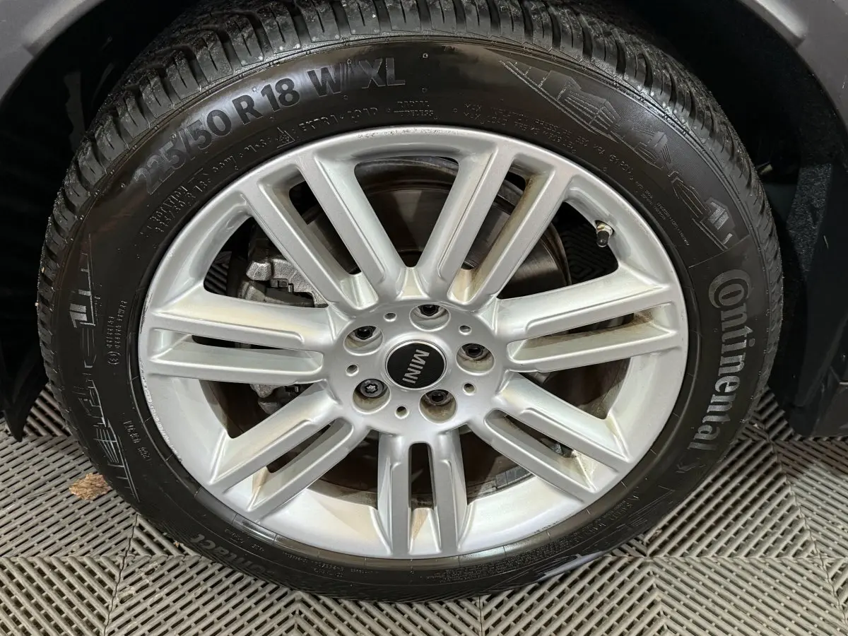 Gros plan sur la jante argentée et le pneu Continental d'un MINI Countryman noir, détail de la roue avant droite.