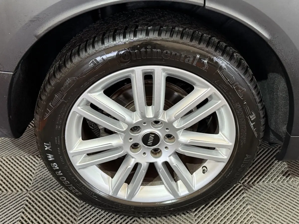 Gros plan sur la roue avant droite d'une MINI Countryman noire, jante alliage argentée et pneu Continental.