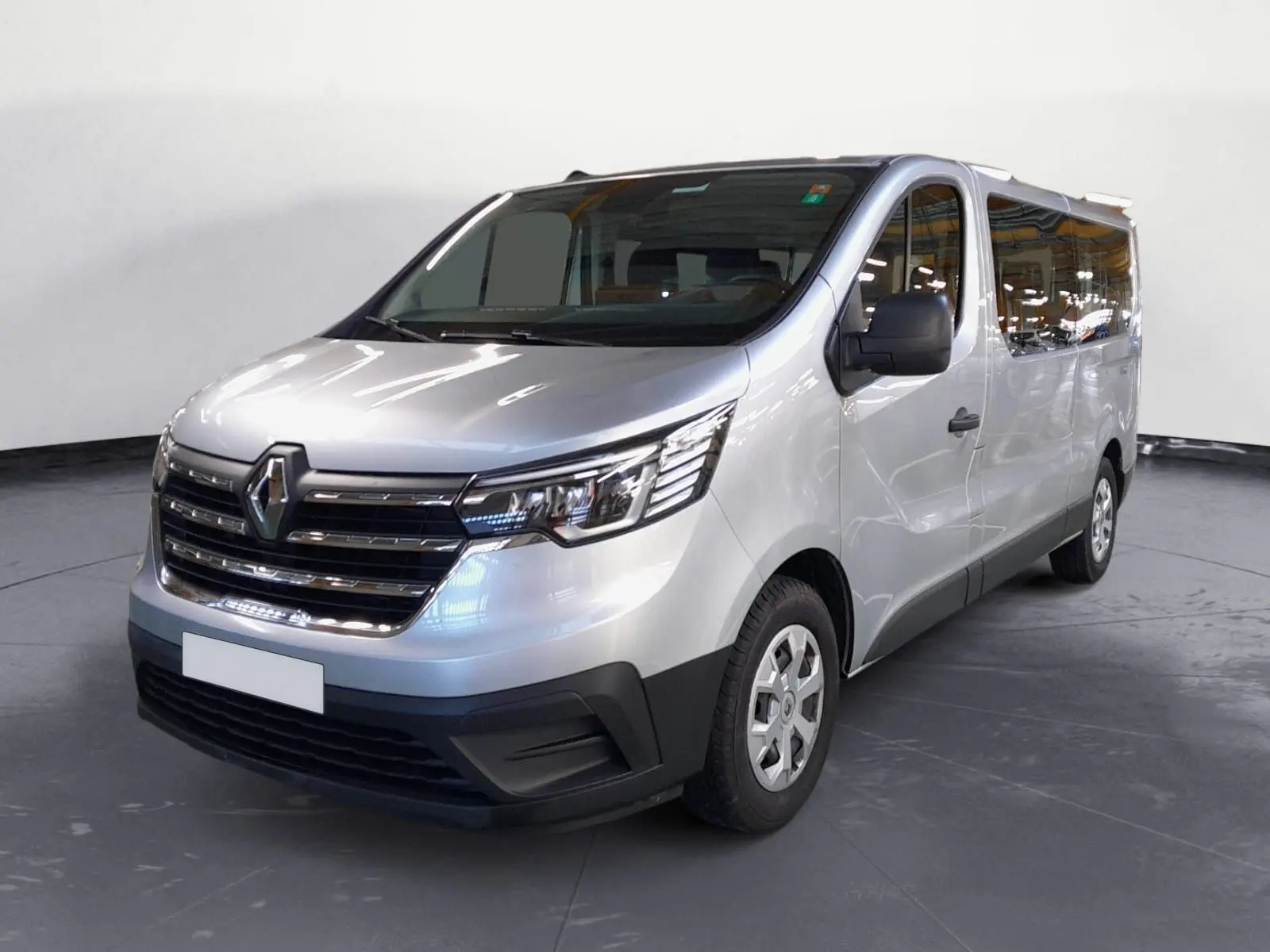 Renault Trafic Combi gris Highland en 3/4 avant droit, avec calandre noire et vitres latérales teintées.
