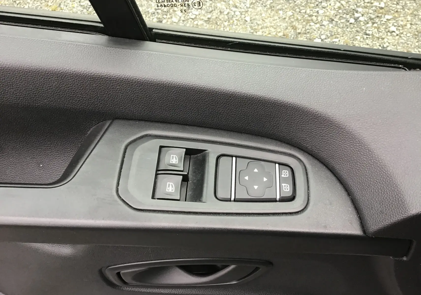 Gros plan sur les commandes électriques des vitres et rétroviseurs sur la porte côté conducteur du Renault Trafic Combi gris Highland 2022.