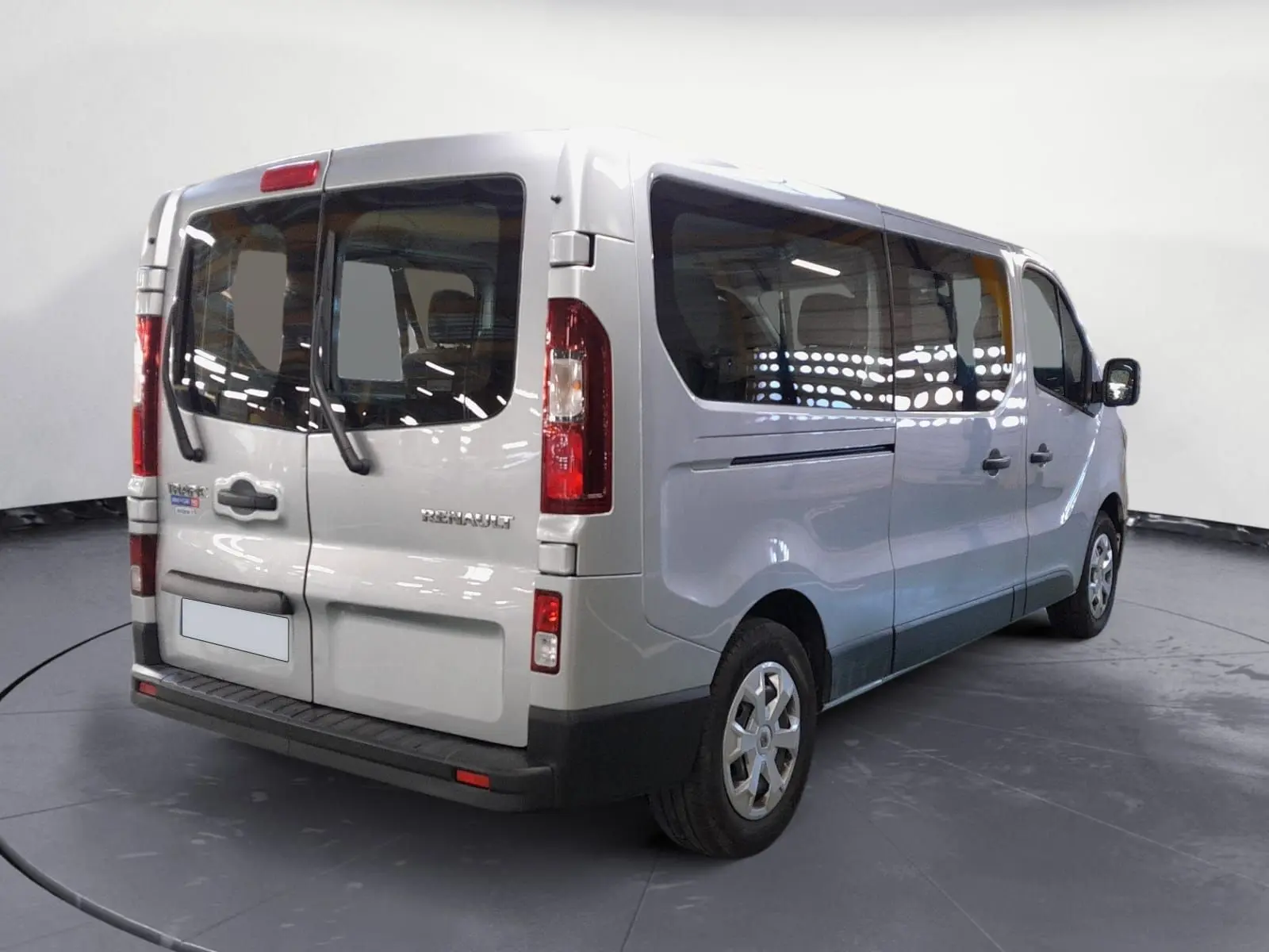 Vue 3/4 arrière droit d’un Renault Trafic Combi gris Highland, avec grandes vitres latérales et portes arrière vitrées.