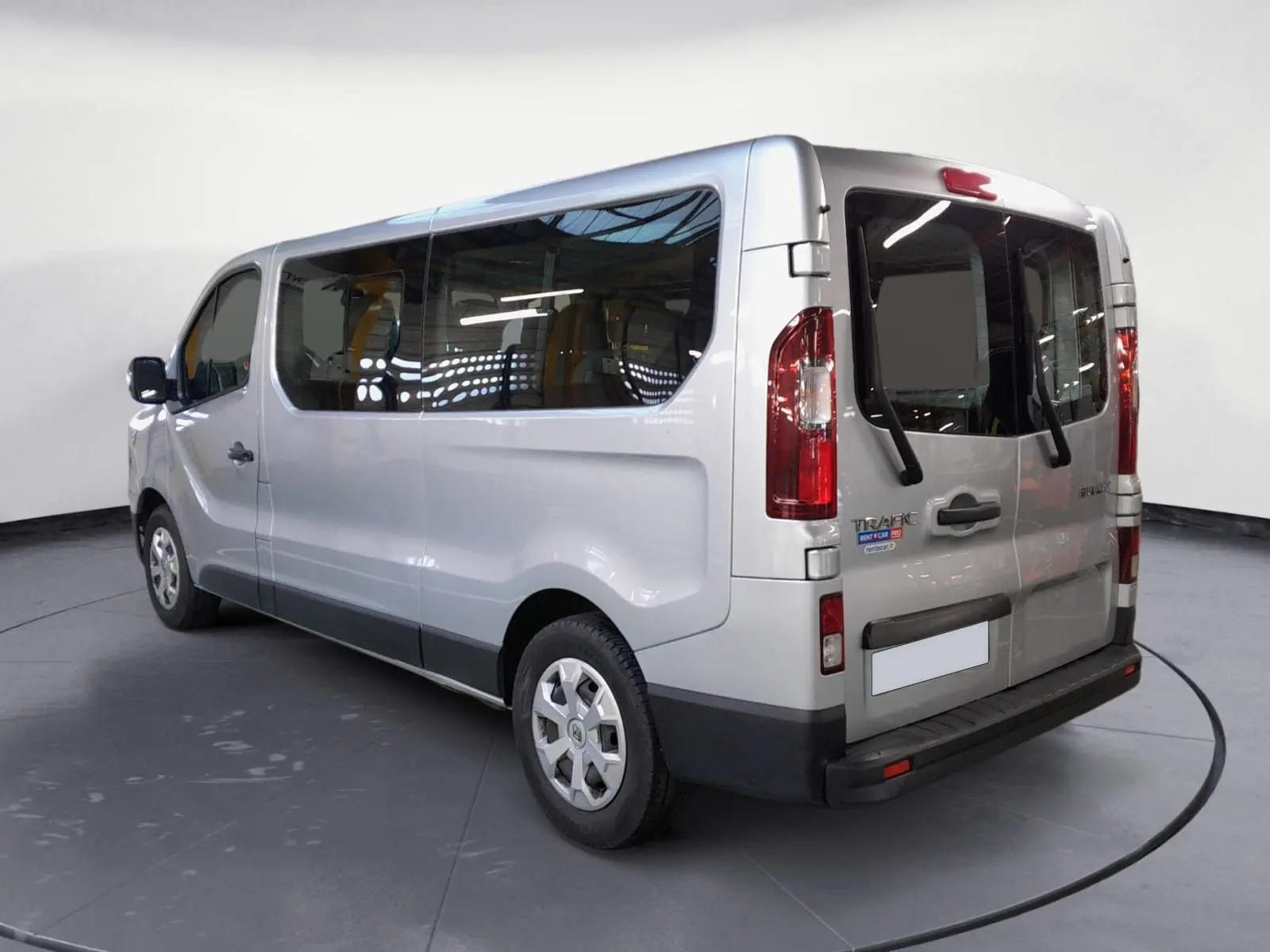 Vue 3/4 arrière droite du Renault Trafic Combi gris Highland, mettant en valeur ses grandes vitres latérales et portes arrière vitrées.