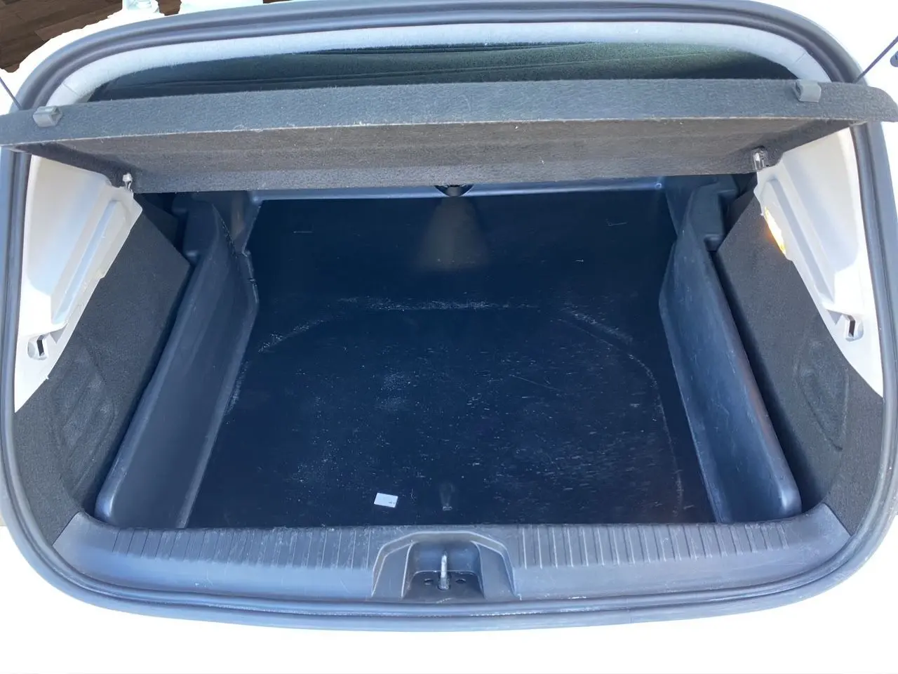 Coffre ouvert vu de dessus d’une Renault Clio V blanche, montrant un espace de rangement vide et propre.