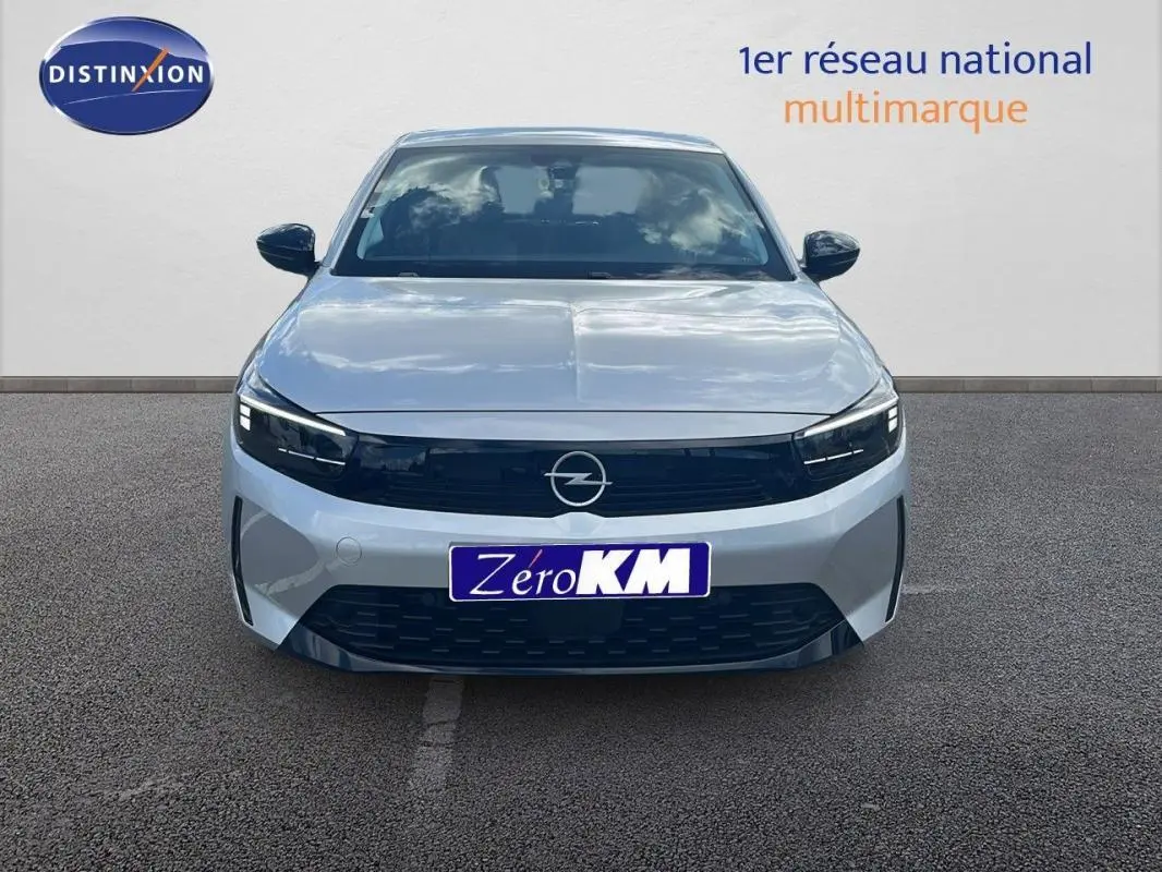 Vue frontale d'une Opel Corsa gris clair 2025 avec calandre noire et phares LED fins sur parking.
