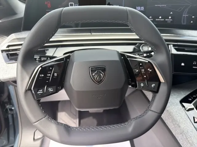 Vue rapprochée du volant cuir multifonctions du Peugeot 3008 bleu 2025 avec logo lion au centre et commandes tactiles intégrées.