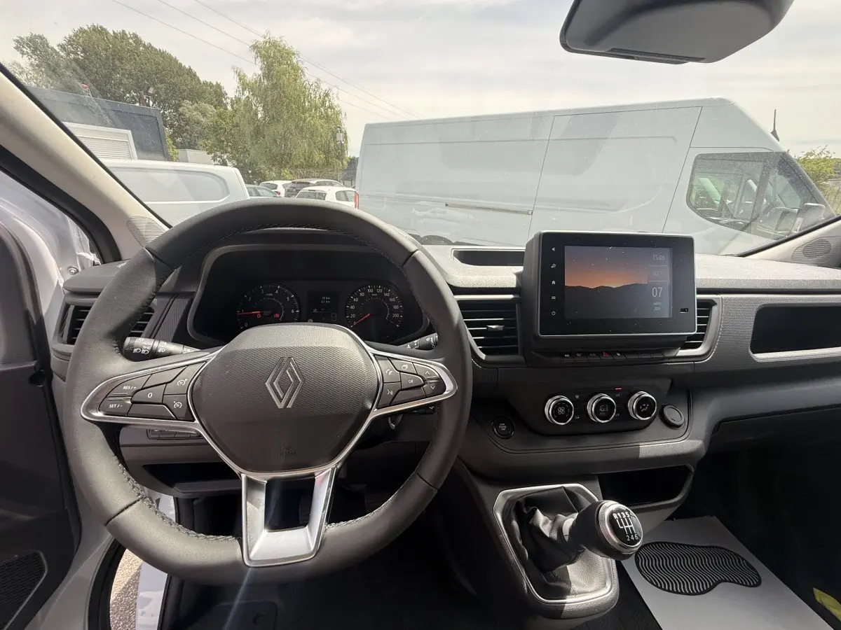 Vue intérieure du tableau de bord et volant multifonctions du Renault Trafic Fourgon blanc, avec écran tactile central et boîte manuelle.