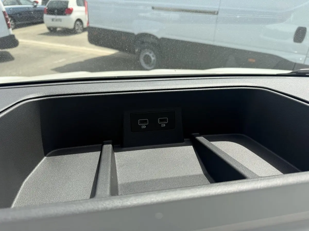 Vue rapprochée de la console centrale du Renault Trafic Fourgon 2025 avec ports USB intégrés, fond noir texturé.