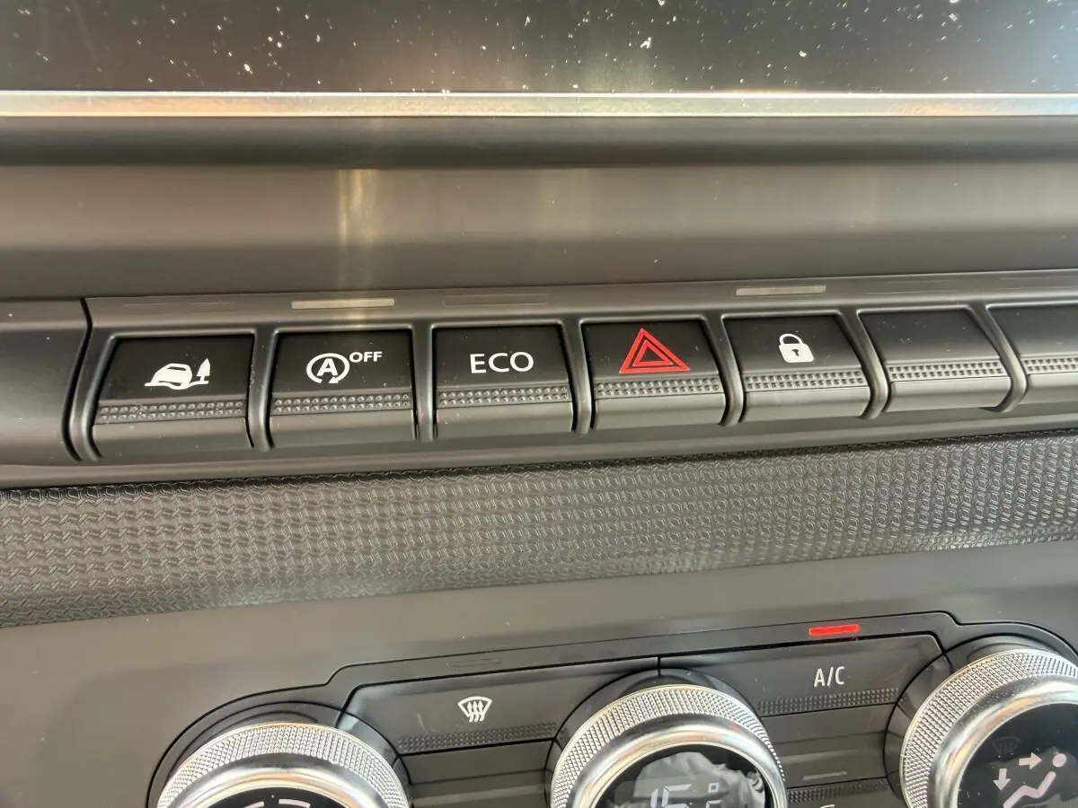 Gros plan sur la rangée de boutons de commande noire et les réglages de climatisation du tableau de bord du Renault Trafic blanc.