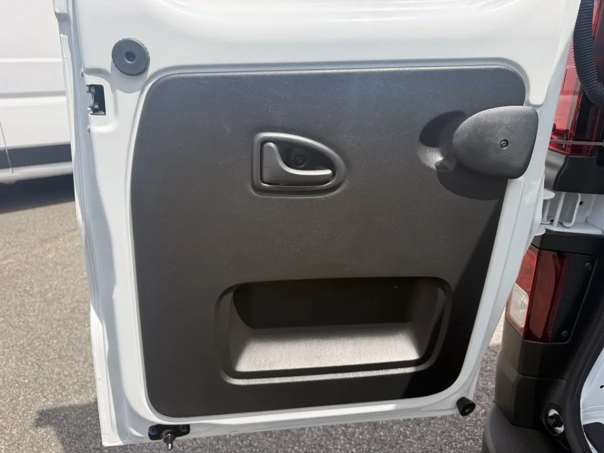 Gros plan sur la porte arrière droite blanche du Renault Trafic Fourgon avec poignée et panneau noir intérieur.