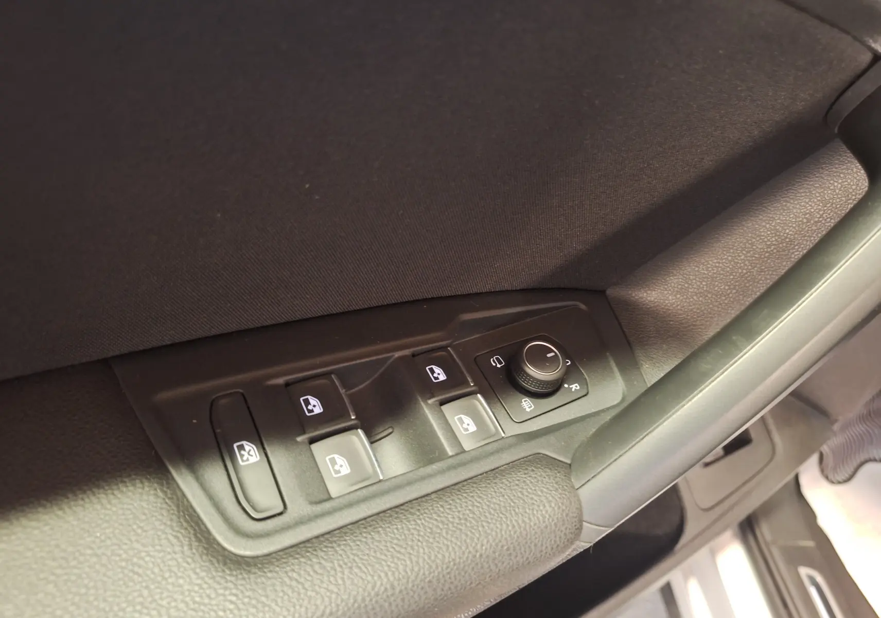 Gros plan sur les commandes des vitres et rétroviseurs côté conducteur du Volkswagen Tiguan gris 2021.
