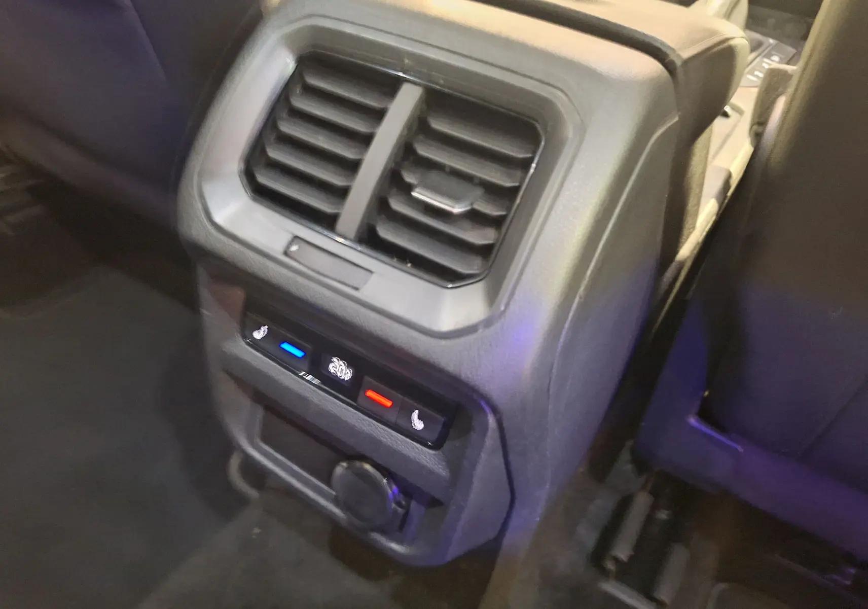 Gros plan sur la console arrière du Volkswagen Tiguan gris, montrant les bouches d’aération et commandes de chauffage des sièges.