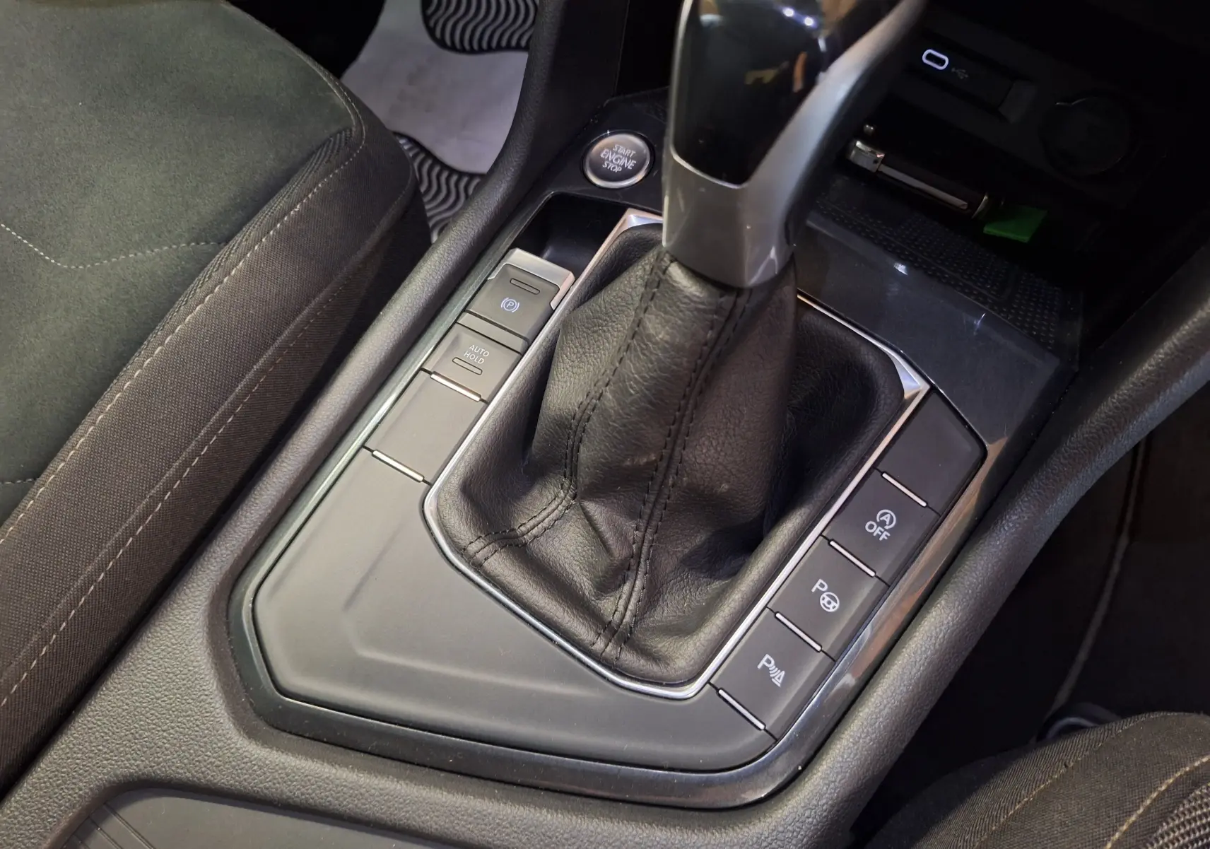 Gros plan sur la console centrale du Volkswagen Tiguan gris, mettant en valeur le levier de vitesse et les boutons de contrôle.