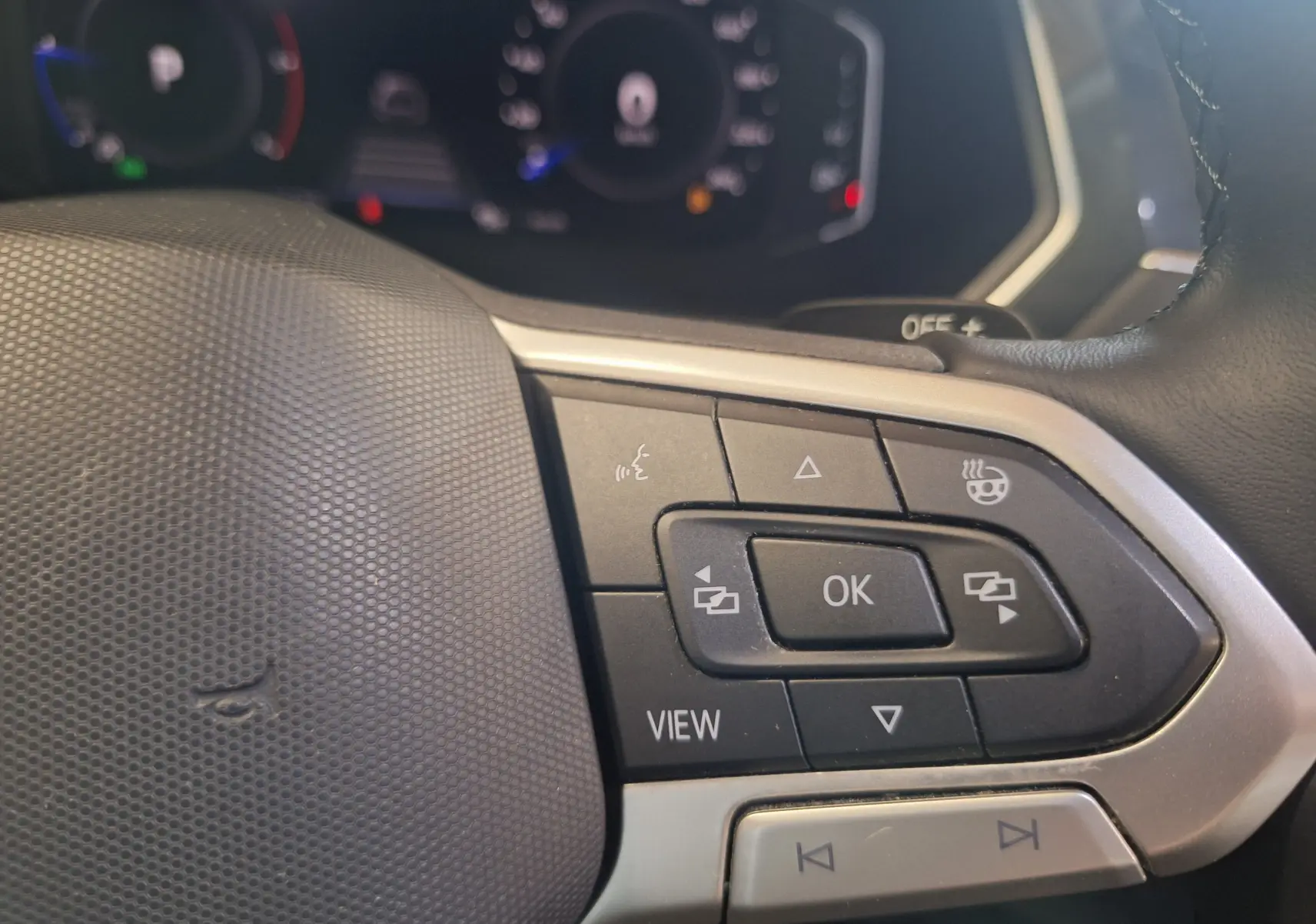 Gros plan sur les commandes multifonctions à droite du volant cuir du Volkswagen Tiguan gris 2021.