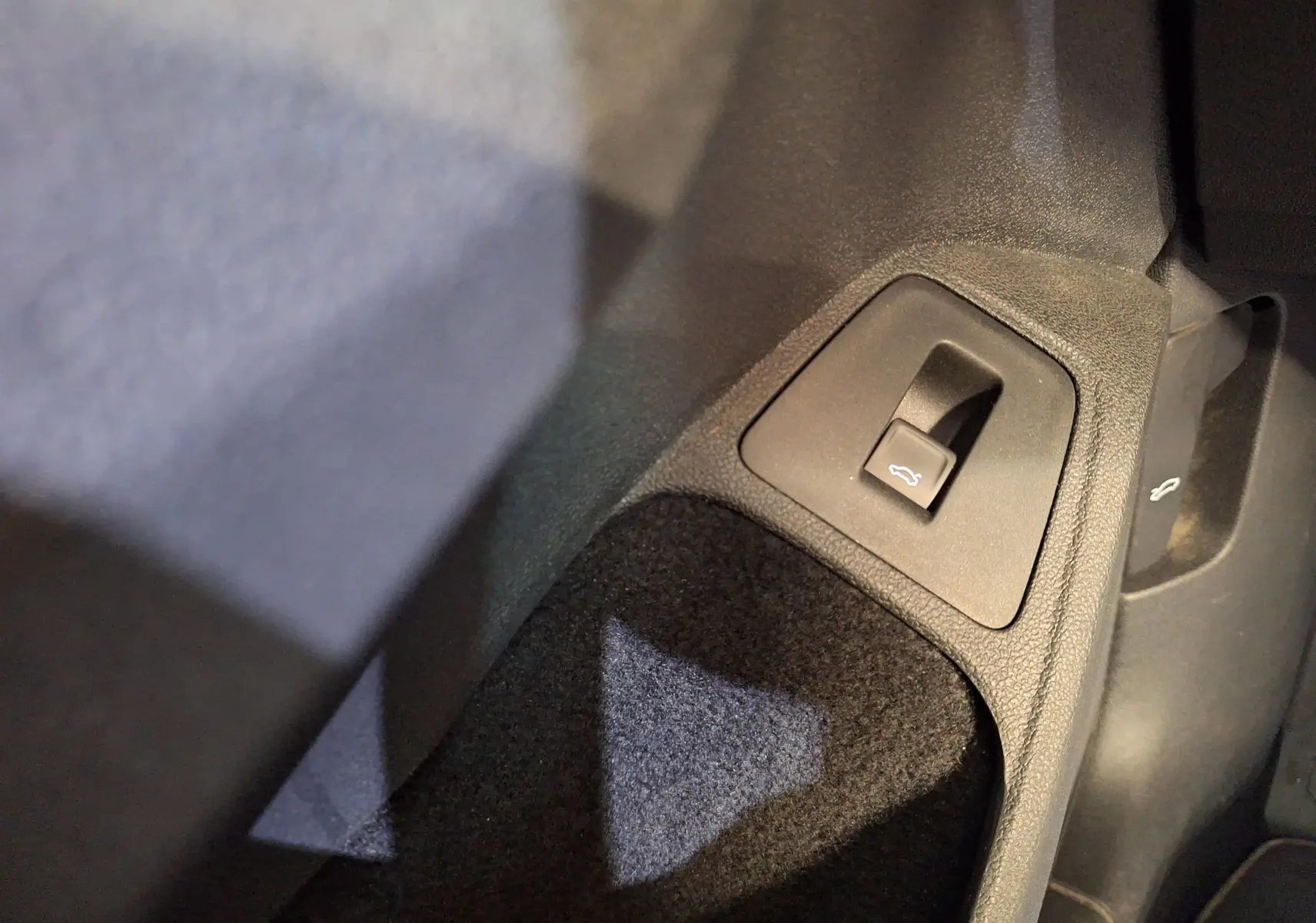 Gros plan sur le bouton d'ouverture électrique du coffre dans l'habitacle du Volkswagen Tiguan gris 2021.