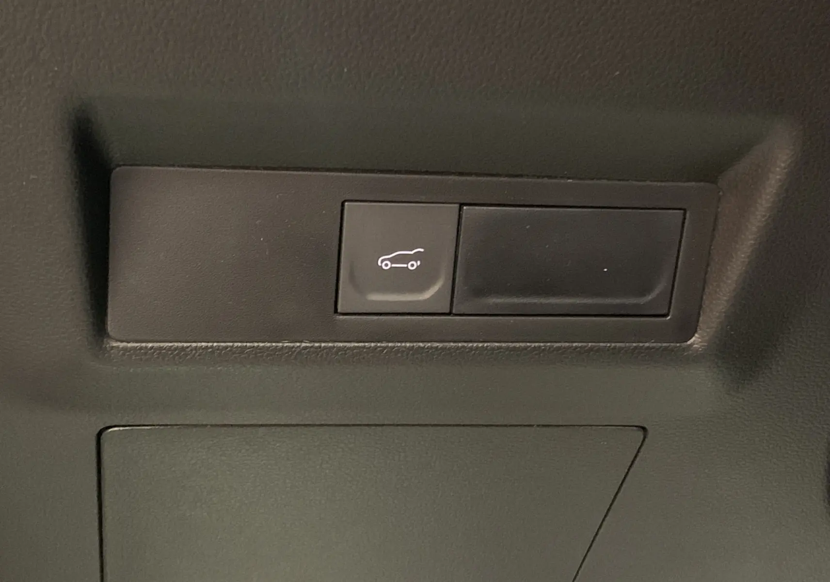 Bouton d'ouverture du hayon motorisé mains libres sur la garniture intérieure du coffre du Renault Symbioz bleu iron.