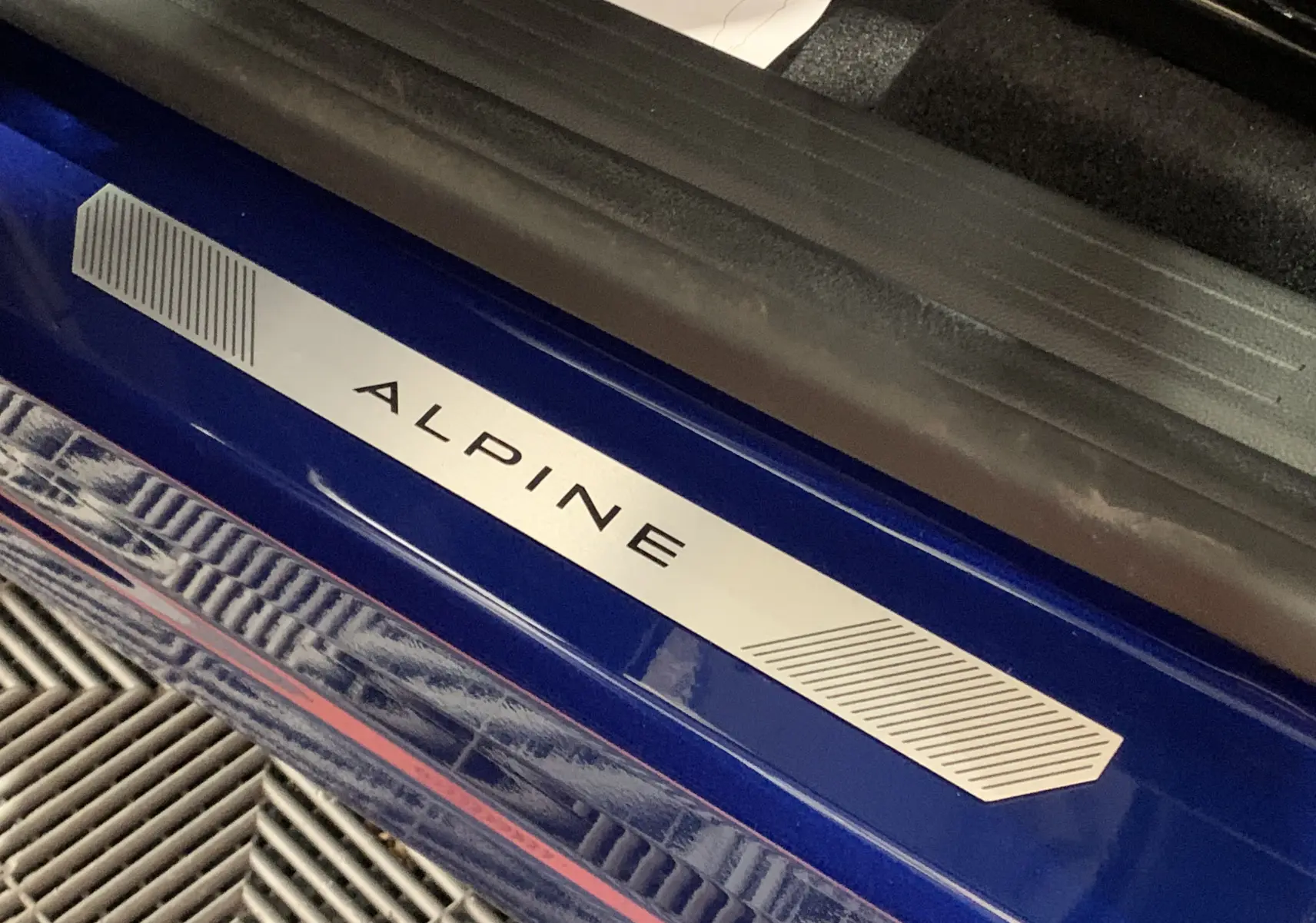 Seuil de porte bleu iron avec logo Alpine en métal sur Renault Symbioz E-Tech Full Hybrid 2025, vue rapprochée côté gauche.