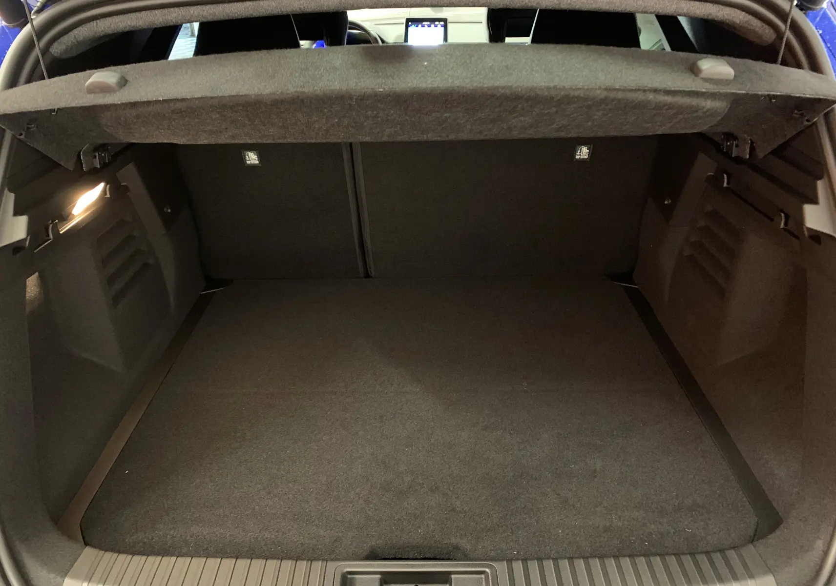 Coffre ouvert vu de l'arrière d'une Renault SYMBIOZ bleu Iron, montrant un espace de chargement propre et spacieux.