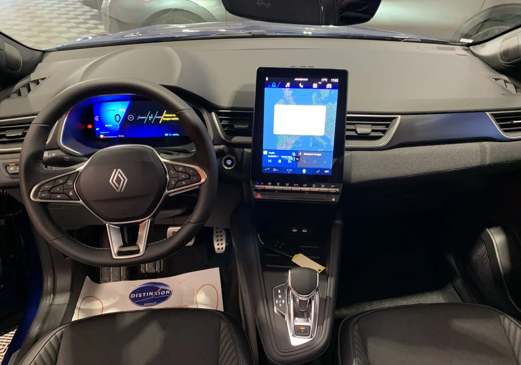 Vue intérieure avant du Renault Symbioz bleu iron, tableau de bord moderne avec écran tactile vertical et volant multifonction.