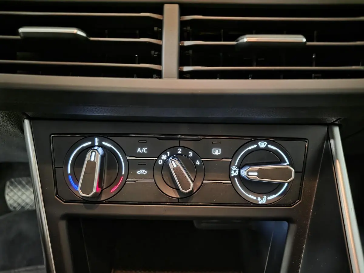 Vue rapprochée des commandes de climatisation manuelle sur le tableau de bord noir du Volkswagen Polo gris 2025.