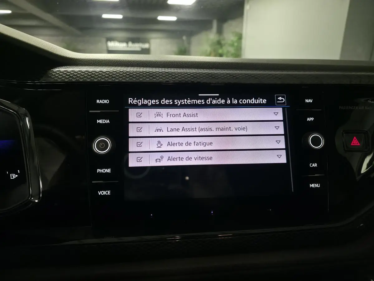 Écran tactile central de la Volkswagen Polo 2025 affichant les réglages d’aides à la conduite, intérieur noir.