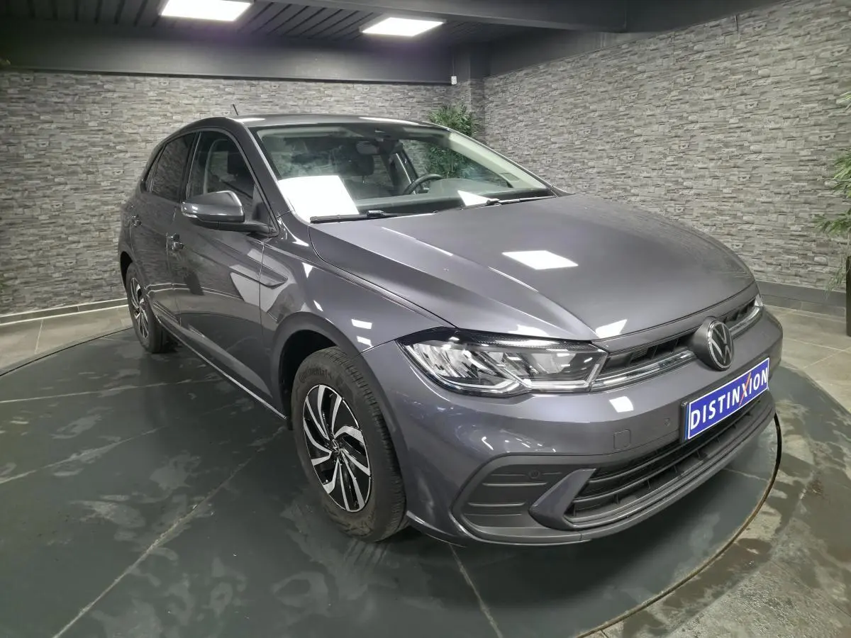 Volkswagen Polo gris métallisé vue 3/4 avant droit avec jantes alliage et calandre chromée.