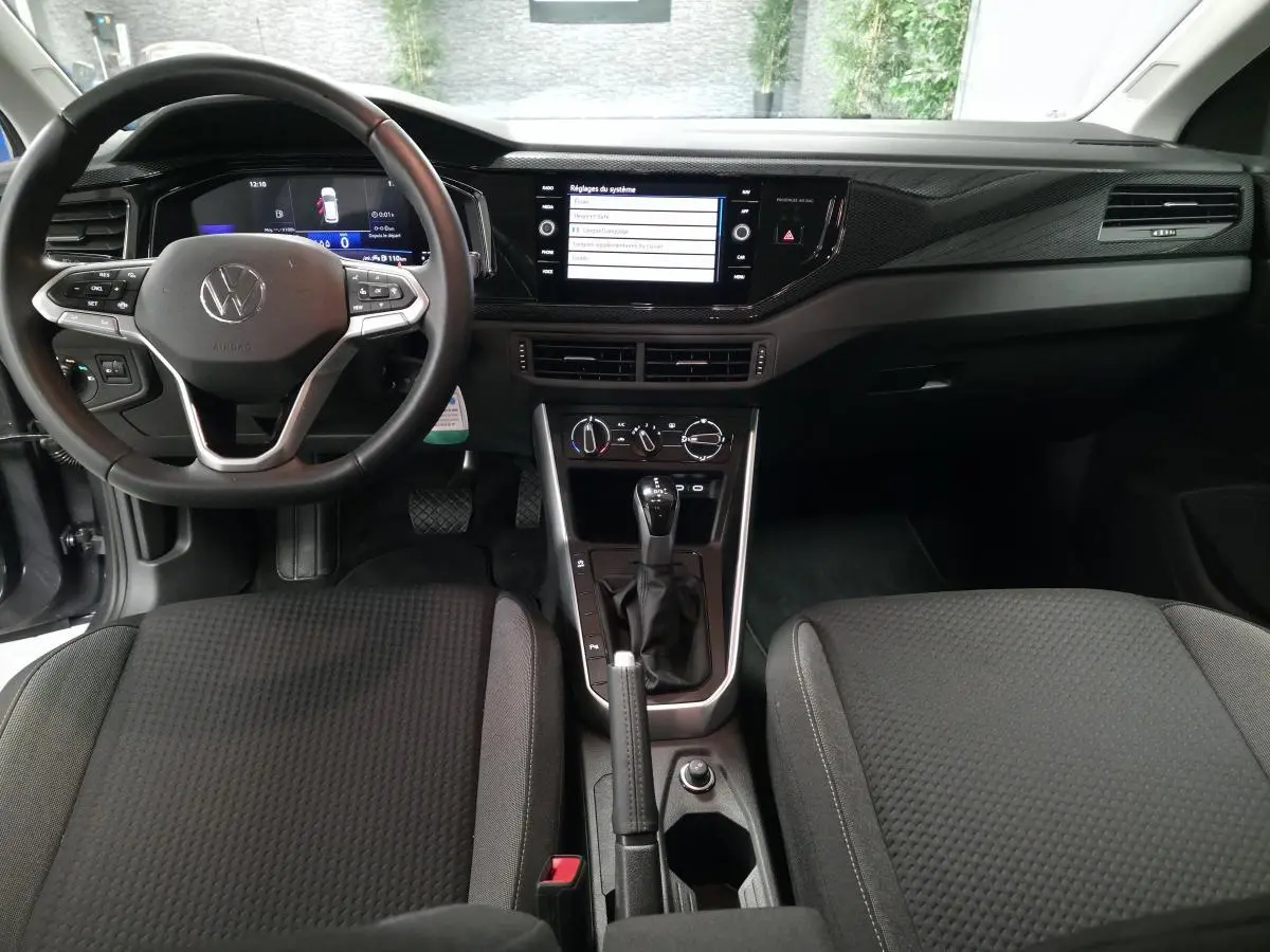 Vue intérieure avant de la Volkswagen Polo gris, tableau de bord avec écran tactile et volant multifonction cuir.