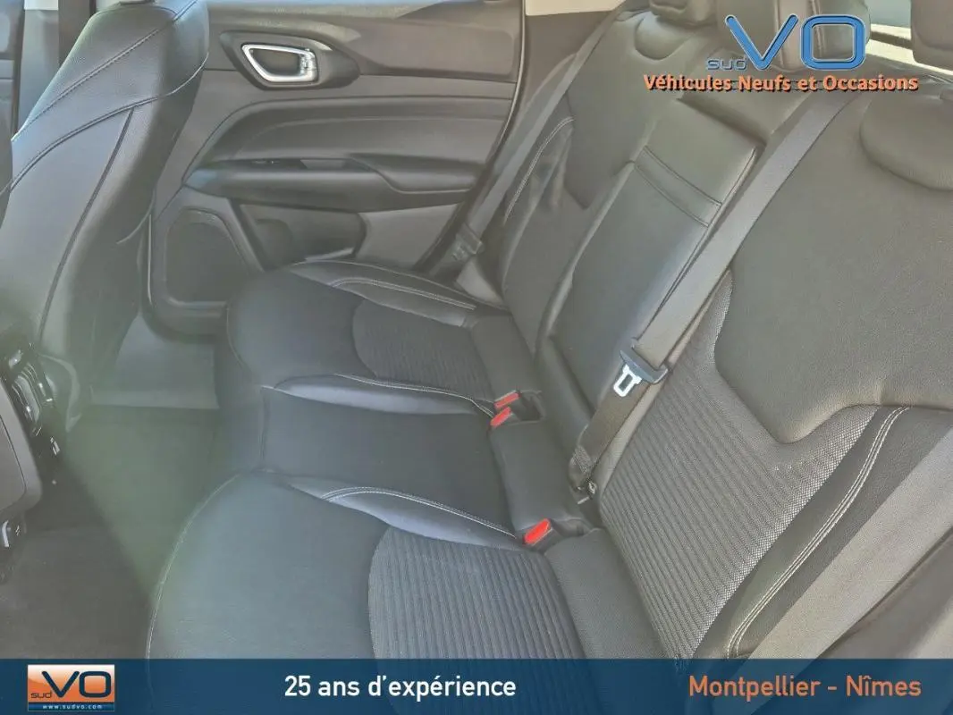 Vue intérieure arrière droite des sièges en cuir noir du Jeep Compass 2023 avec ceinture de sécurité et accoudoir central visible.