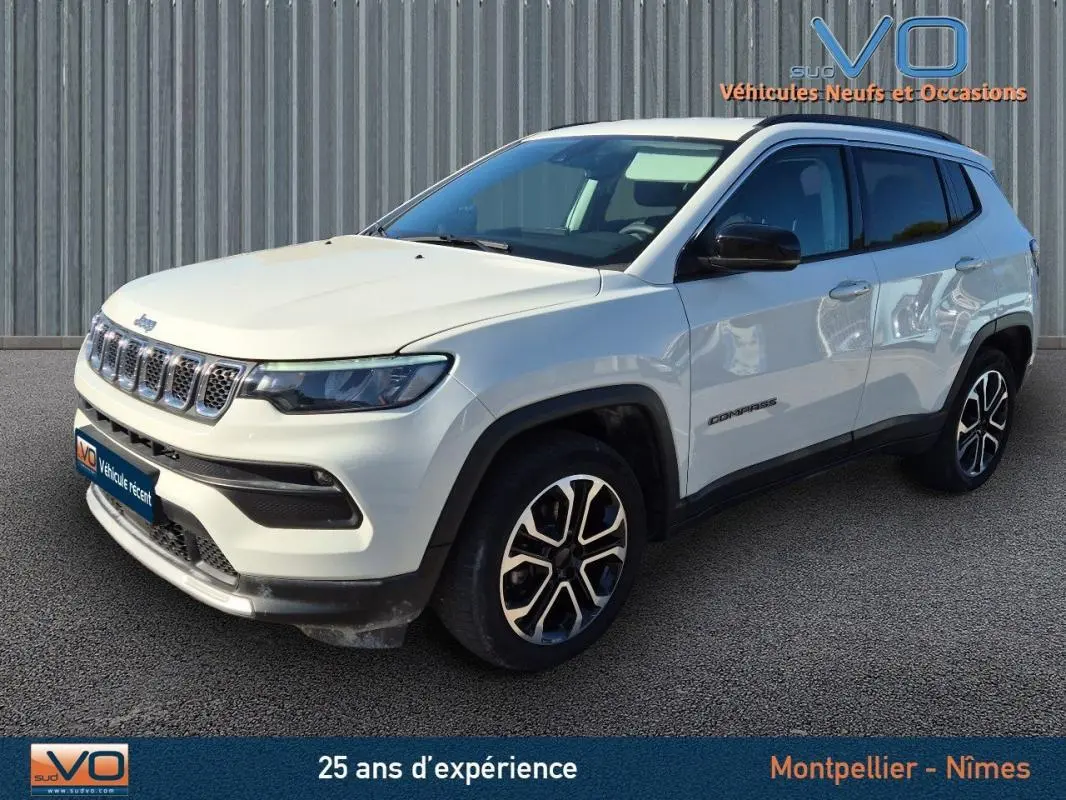Jeep Compass blanc en 3/4 avant droit, avec jantes 18 pouces et rétroviseurs noirs sur fond urbain.