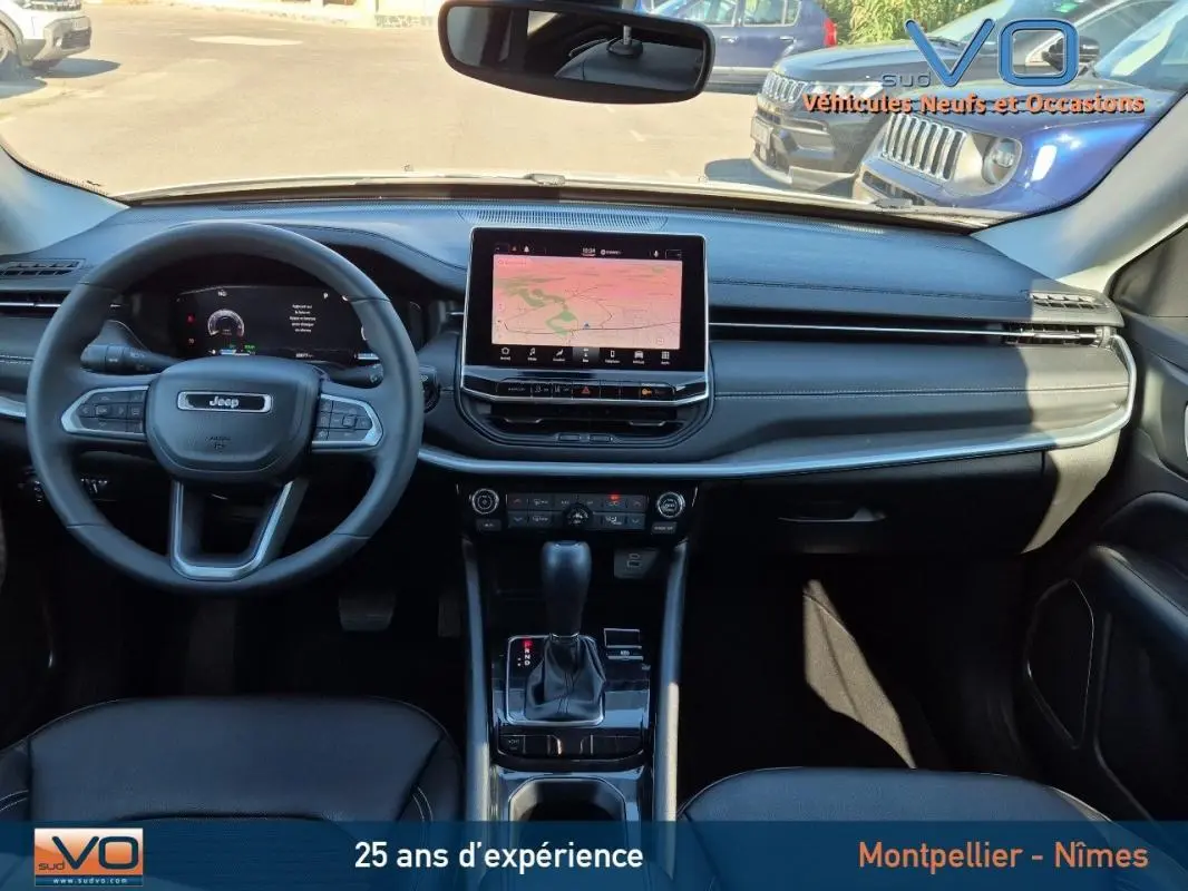 Intérieur du Jeep Compass 2023 vu de face, tableau de bord noir avec écran tactile central et volant multifonction.