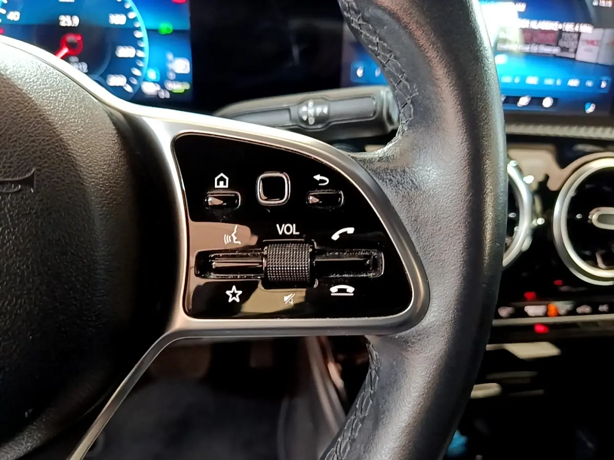 Gros plan sur le volant cuir noir côté gauche de la Mercedes Classe A 250 e avec commandes tactiles et tableau de bord digital.