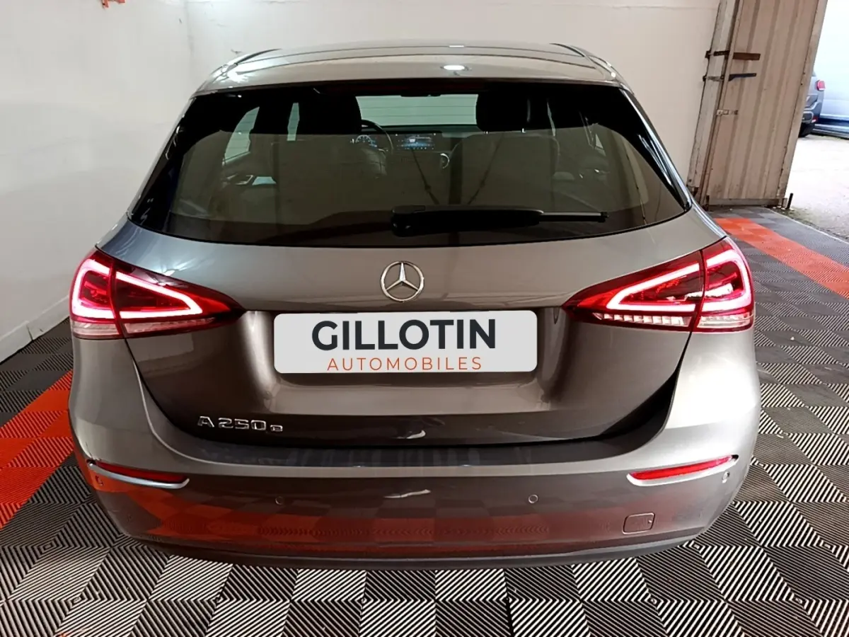 Vue arrière d'une Mercedes Classe A 250 e Business Line gris foncé avec feux arrière LED allumés dans un garage.