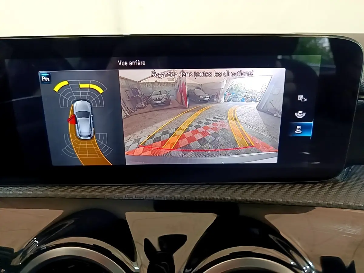 Écran multimédia affichant la caméra de recul et l'aide au stationnement du Mercedes Classe A gris foncé en intérieur.