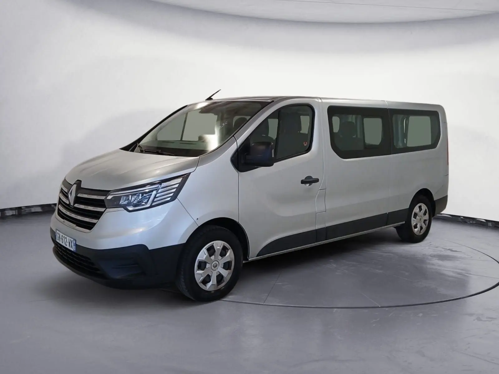 Renault Trafic Combi gris clair métal vu en 3/4 avant droit, avec grandes fenêtres latérales et jantes acier.