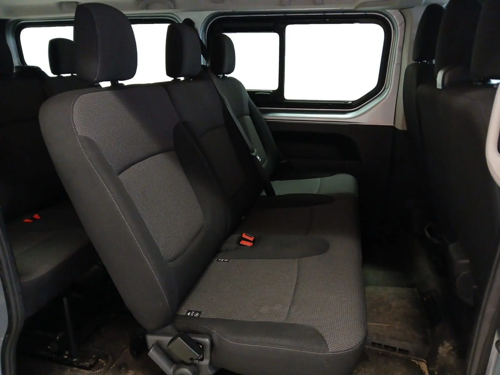 Vue intérieure côté droit des sièges arrière gris foncé du Renault Trafic Combi L2 2023, avec fenêtre latérale visible.