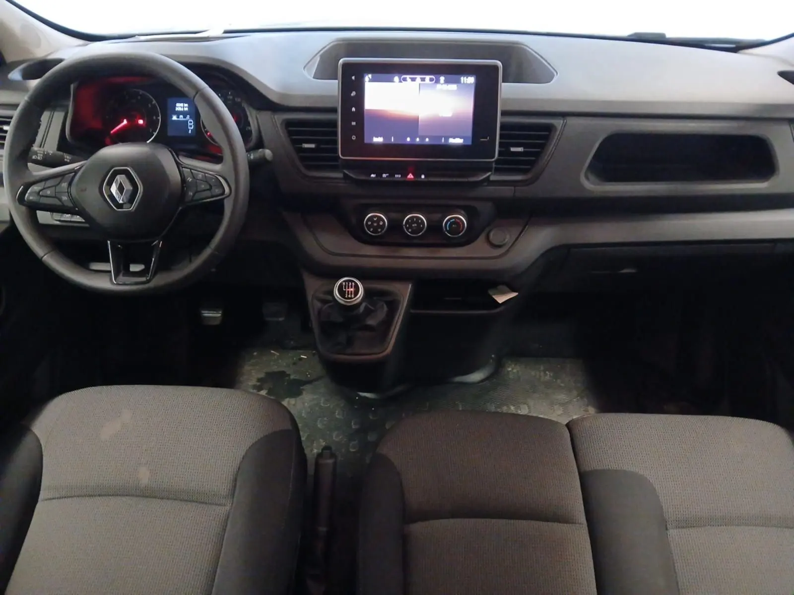 Vue intérieure frontale du Renault Trafic Combi 2023 avec tableau de bord gris, volant multifonction et écran tactile central 8 pouces.