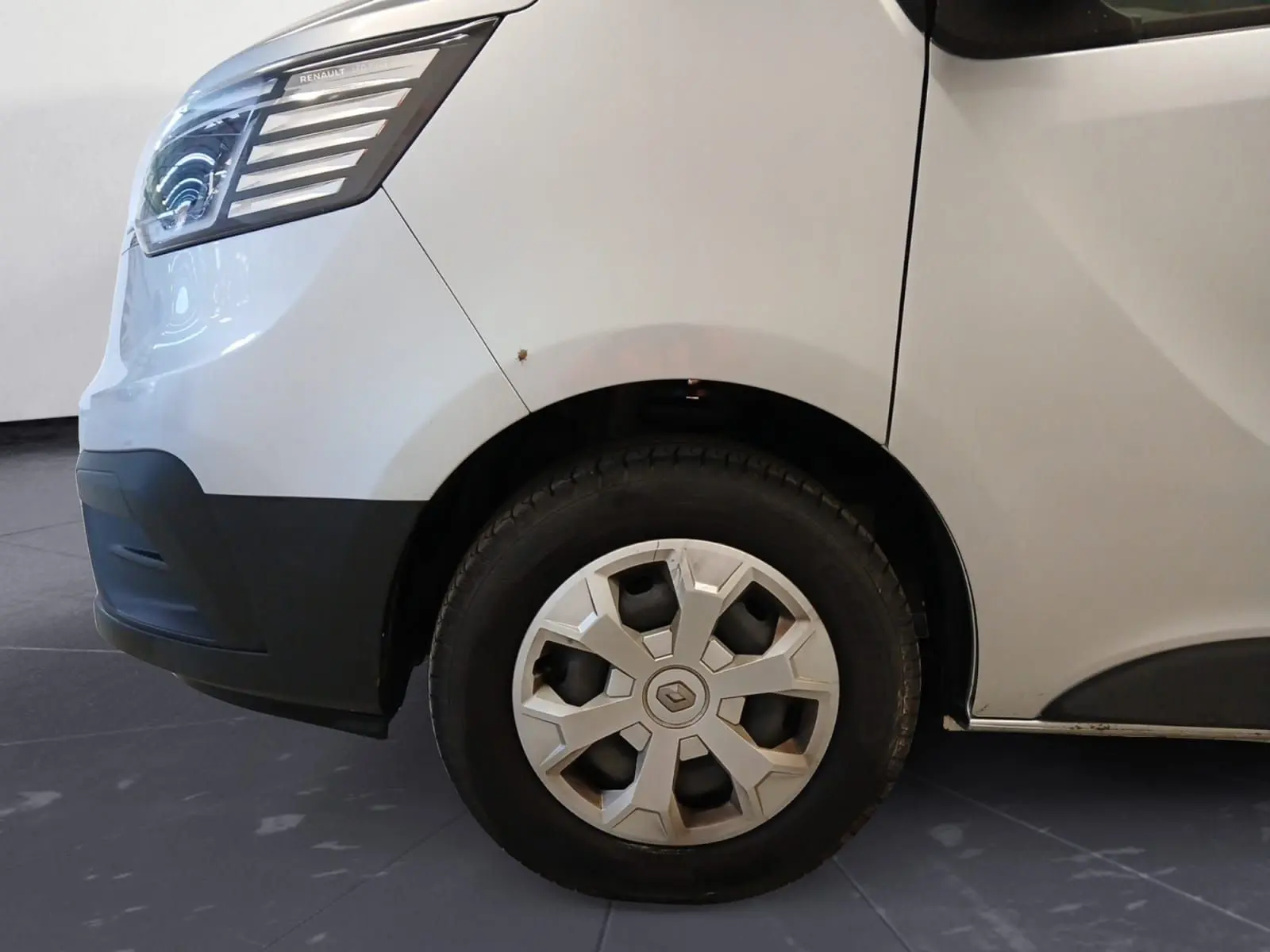 Gros plan sur la roue avant gauche et le passage de roue d’un Renault Trafic Combi gris clair métal, 2023.