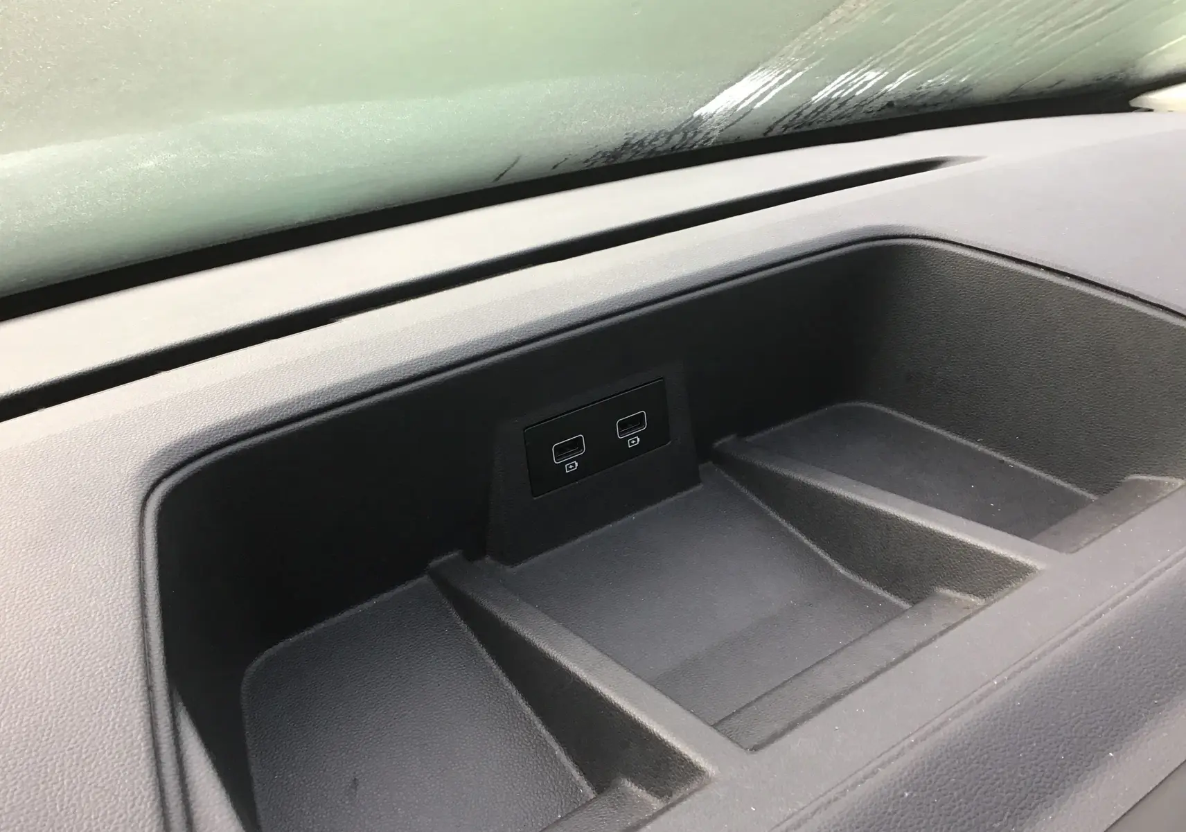 Gros plan sur le rangement central du tableau de bord du Renault Trafic Combi gris clair, avec deux ports USB visibles.