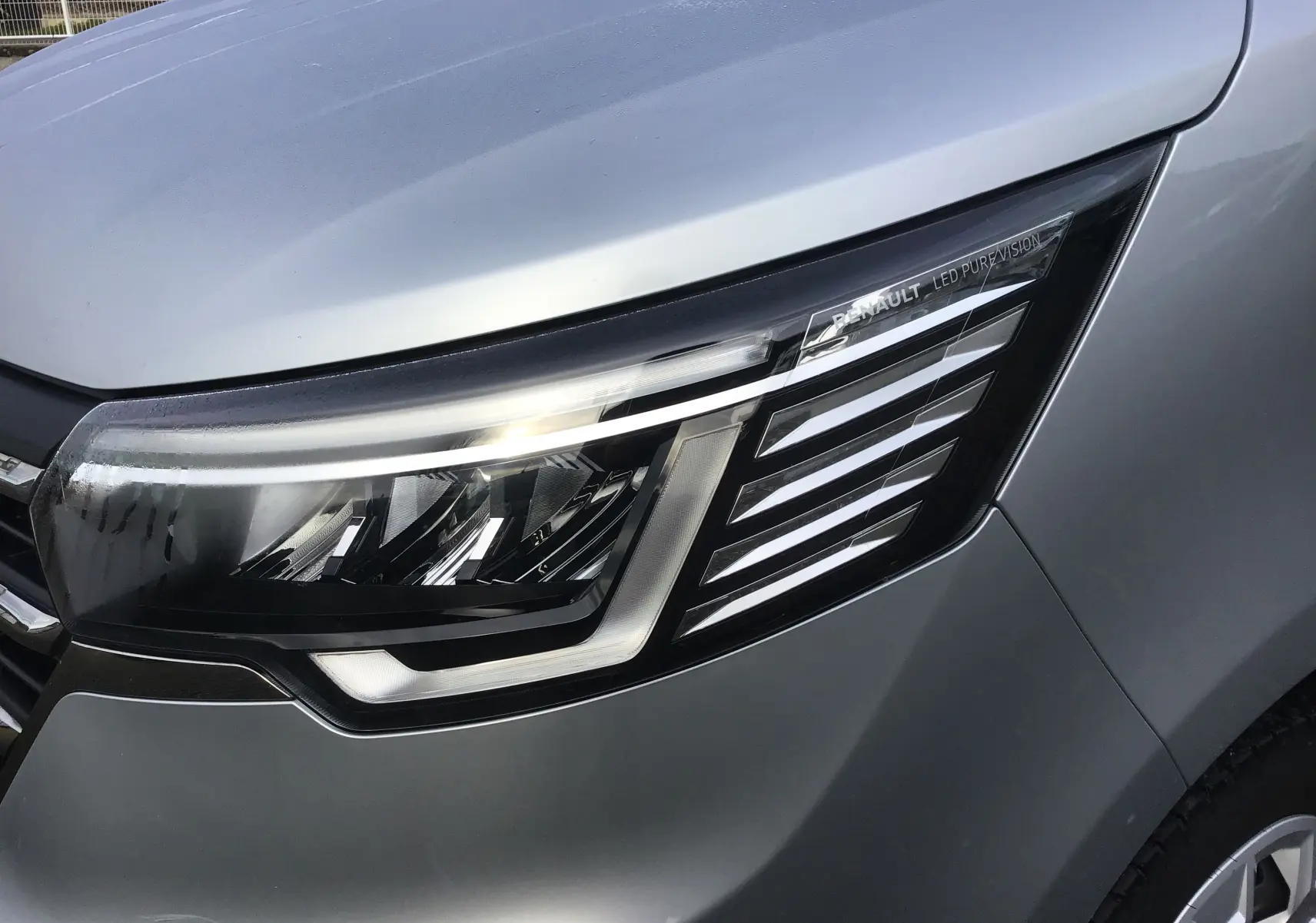 Gros plan sur le phare avant droit LED du Renault Trafic Combi gris clair métal, soulignant son design moderne et épuré.