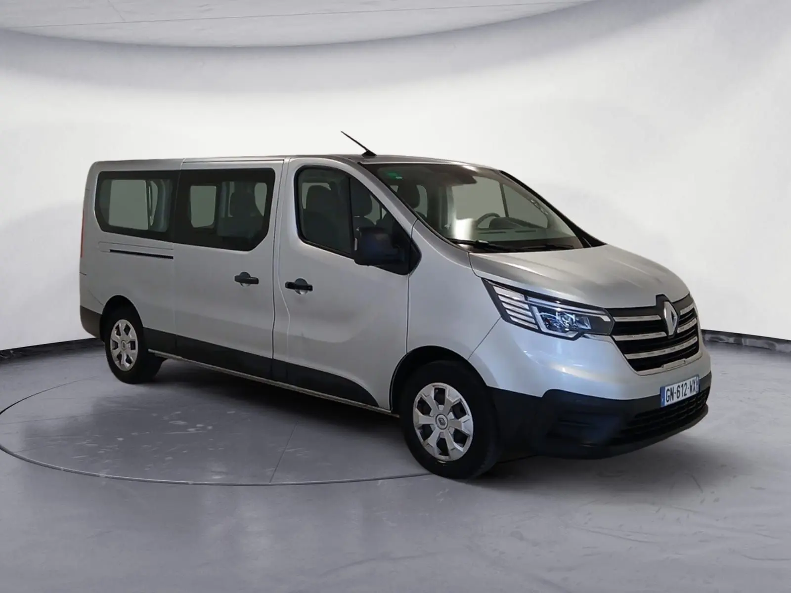 Renault Trafic Combi gris clair métal vu en 3/4 avant droit, avec calandre noire et vitres teintées arrière.